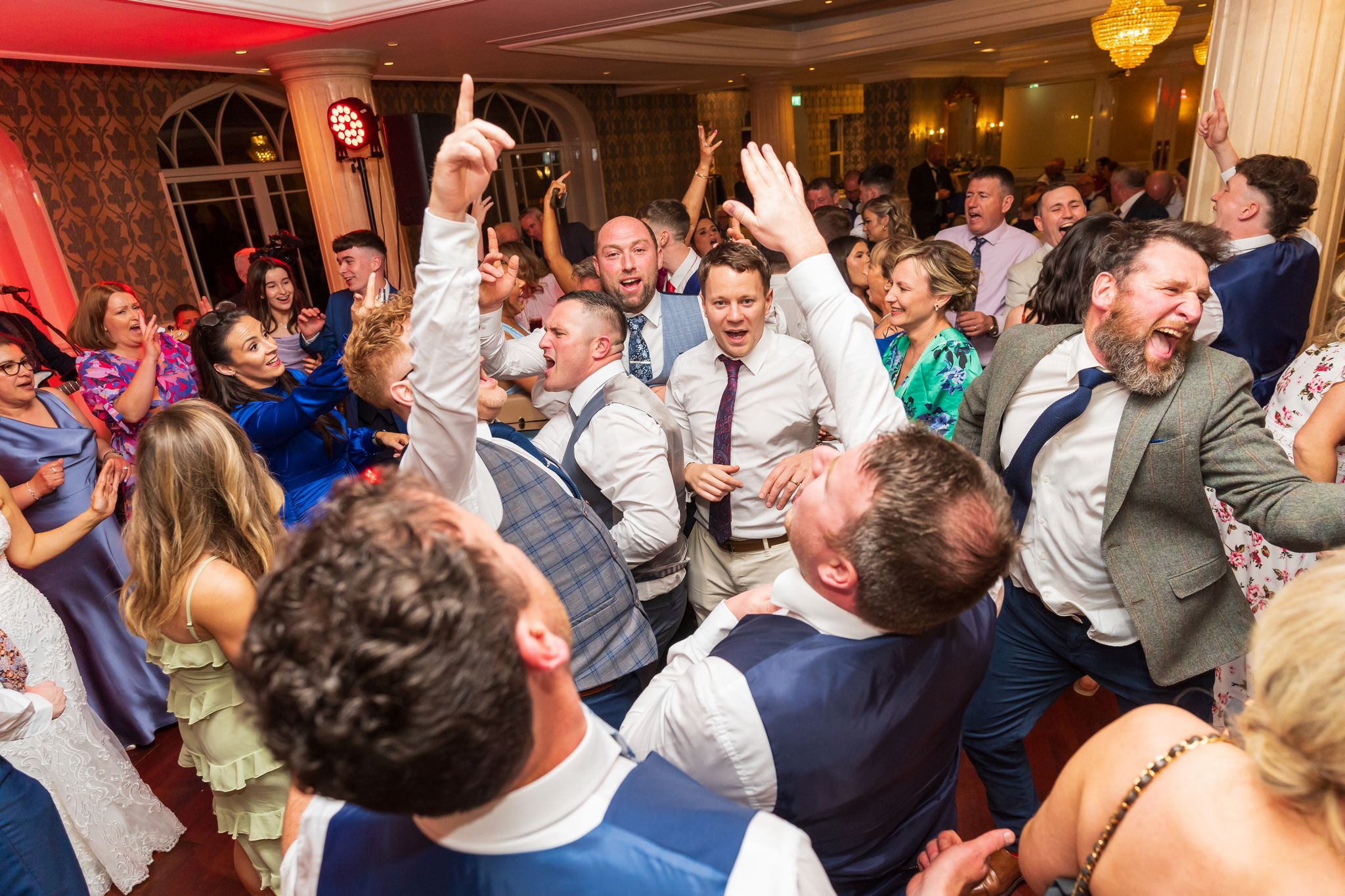 Bride and groom mid first-dance with guests blurred around the dance floor