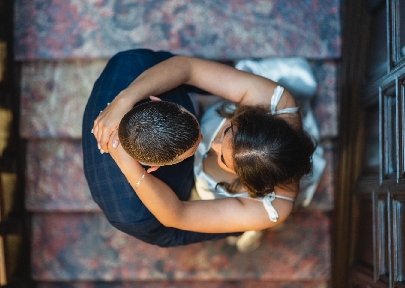 Overhead shot of the couple slow-dancing on a richly patterned rug, taken from directly above