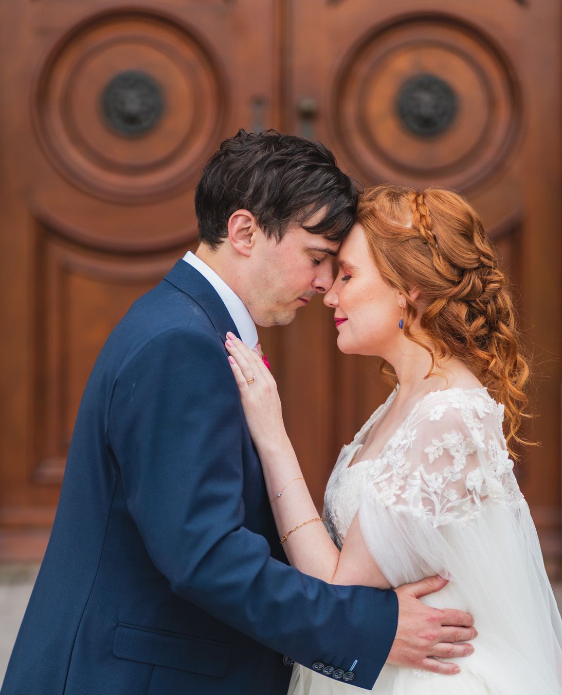 Couple resting their foreheads together in front of carved wooden church doors