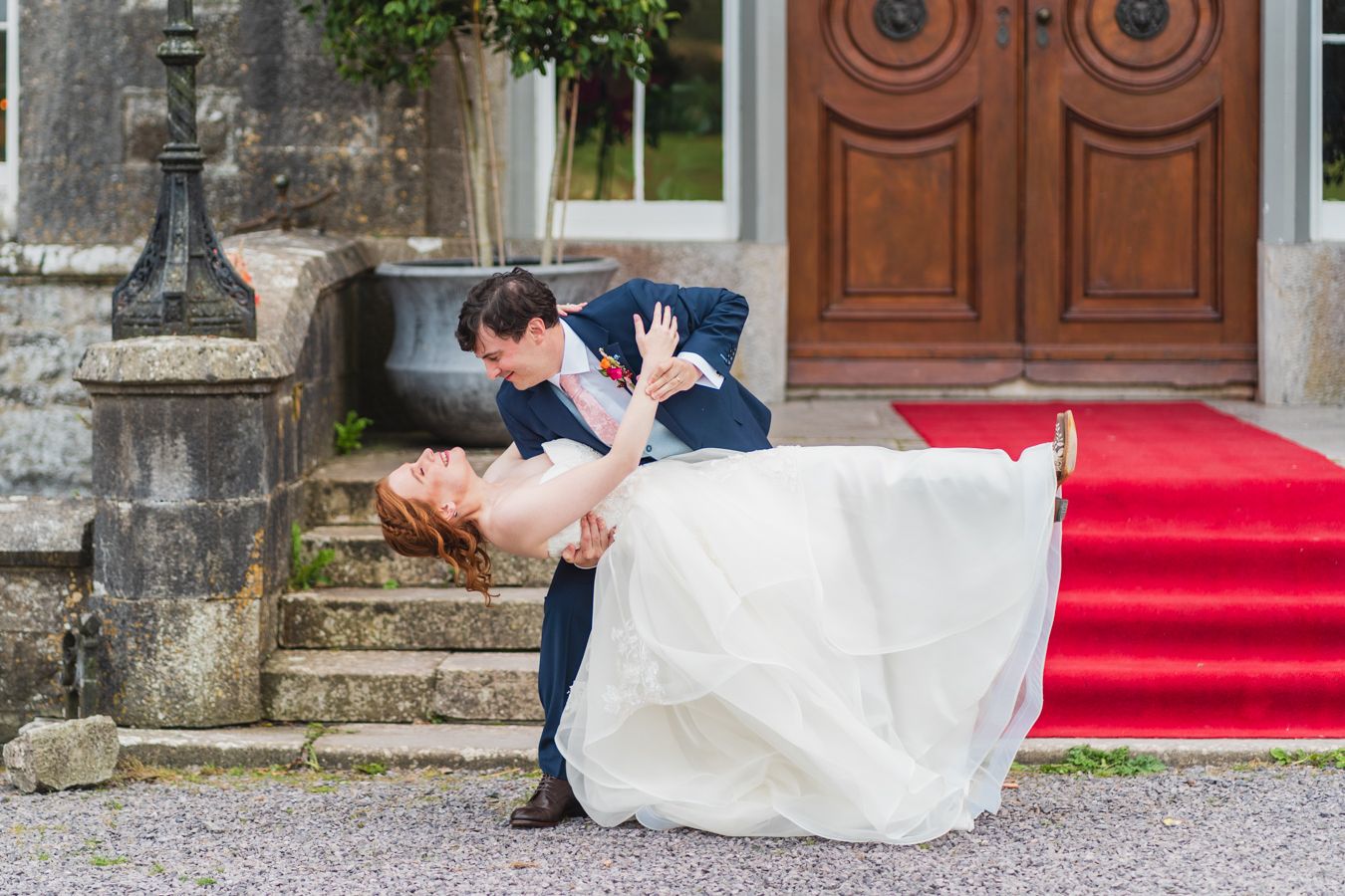 Groom dipping the bride in a playful dance pose on the red carpet at the venue entrance